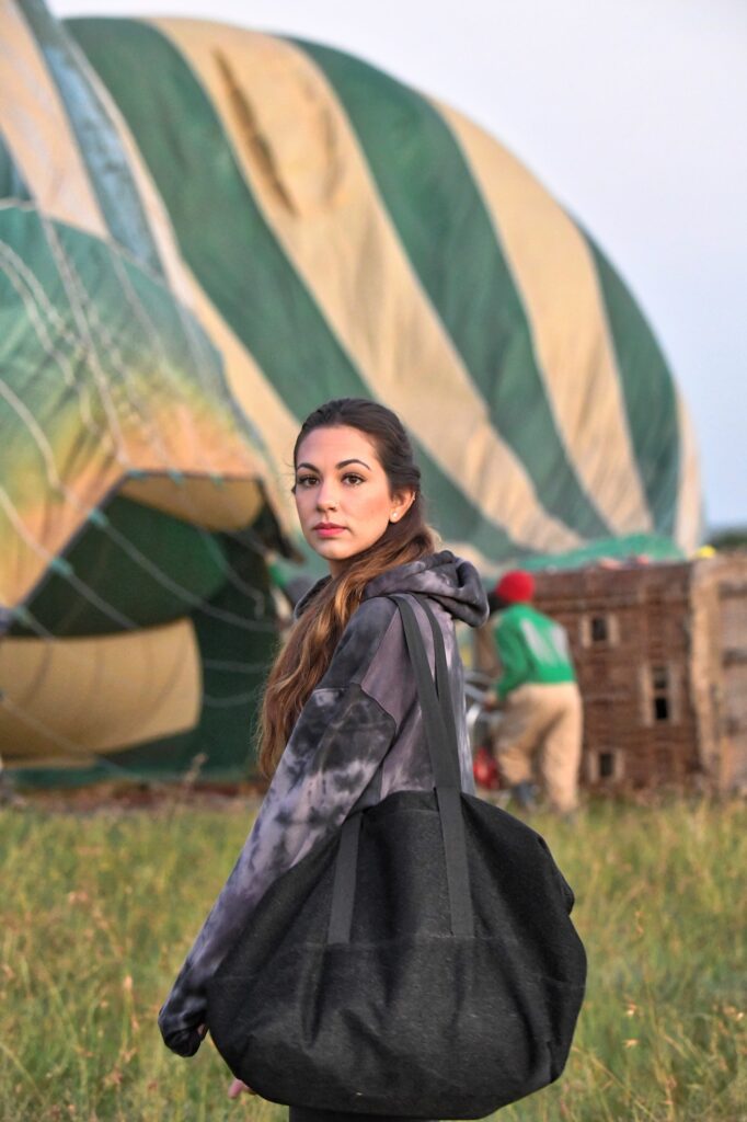 Young adventurous millennial tourist getting ready for sunrise balloon ride on her safari in Africa